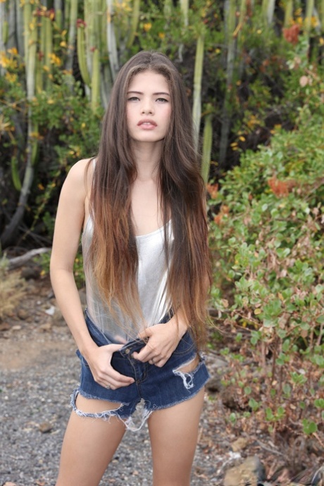 Skinny Latina teen Irene Rouse posing in her sexy ripped denim shorts outside