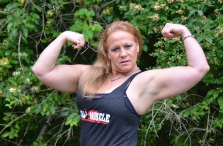Mature bodybuilder Stunning Summer shows off her strong body outdoors