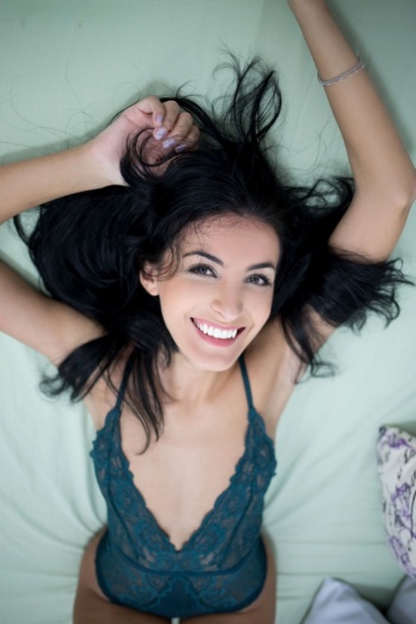 Raven haired pretty babe poses in lacy bodysuit and poses on a bed