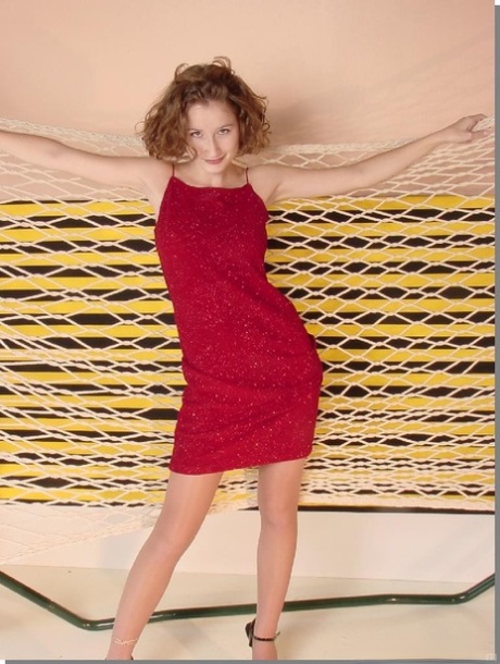 Die brünette Teenagerin Angeline zieht ihr rotes Kleid aus und zeigt ihren Arsch in Nylons