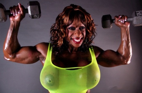 Muskuløs ibenholt Yvette Bova løfter vægte, mens hun viser sine enorme meloner frem