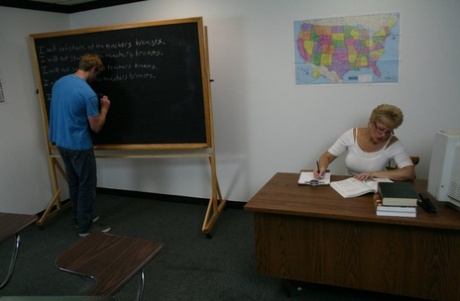 A professora Tracy Lick, de cabelo curto, ordenha a pila grande de um aluno tímido durante a aula