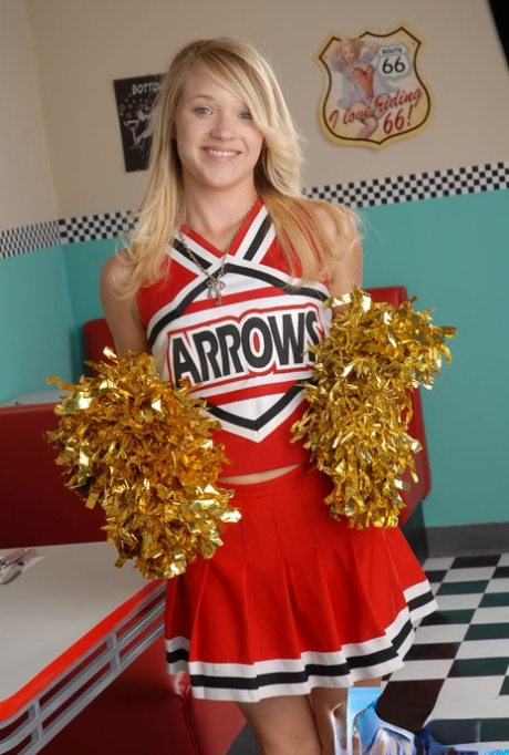 Die süße College-Blondine Tegan Summers posiert in einem Cheerleader-Outfit in einem Diner