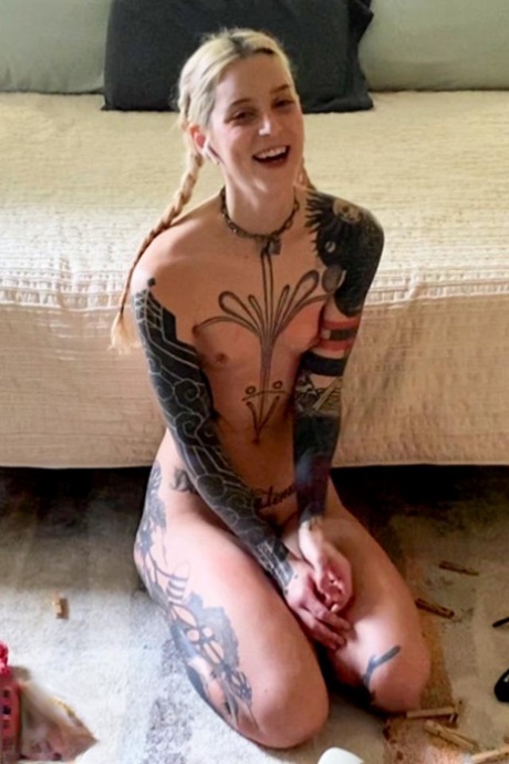 La ragazza snella con tatuaggi Cam Damage prova gli strumenti bondage sul pavimento