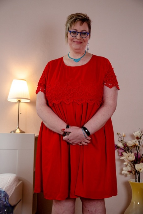 Denisa, een oude dikkerd met een bril, trekt haar rode jurk uit en laat haar enorme tieten zien