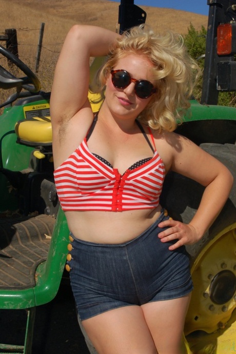 La rubia regordeta Poppy Cox se desnuda en un tractor y muestra sus curvas y su coño peludo