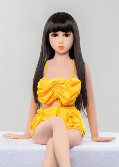 Petite brunette sexdocka Carys strips poserar naken och i en söt gul outfit
