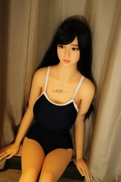 La dolce sex doll asiatica Monica in posa con il suo sexy vestito attillato sul divano