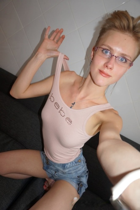 Amatör tonåring i glasögon smeker sina söta bröst i hemlagad sexig selfie action