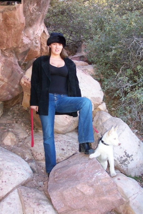 Une jeune femme amateur se promène dans la nature en jeans, manteau et chemise.