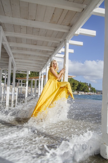 Blonde hottie Milena Angel zeigt ihre großen Titten unter einem Dock in einem gelben Kleid