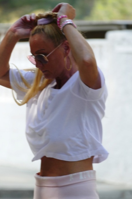Зрелая блондинка в солнцезащитных очках Natalie K показывает свои большие сиськи и пизду на открытом воздухе