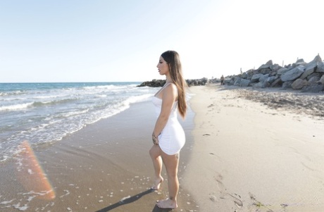 Brune latina med tatoveringer Roma Amor viser sine naturlige bryster frem på stranden
