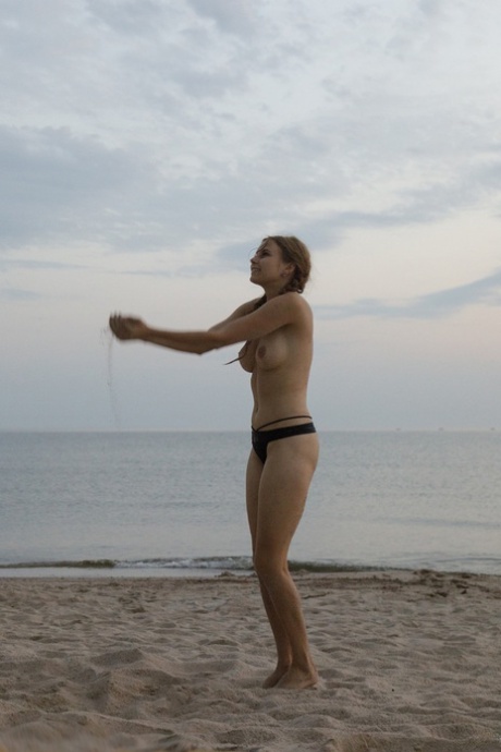 Amadora despe o biquíni e mostra o seu corpo atraente na areia da praia