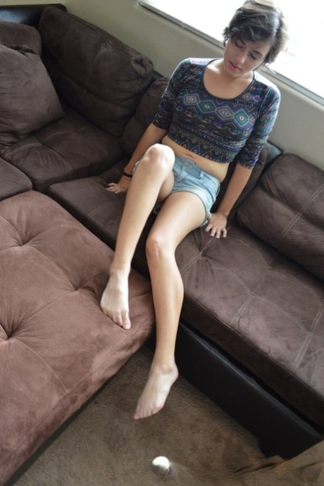 Une jeune fille amateur se déshabille entièrement et se masturbe avec un godemiché sur le canapé.