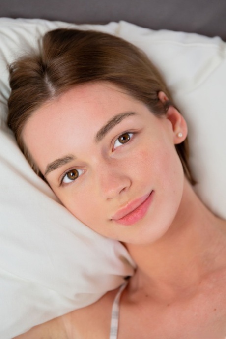 La beauté adolescente Amy Moloko enlève sa chemise et pose les fesses nues sur le lit.