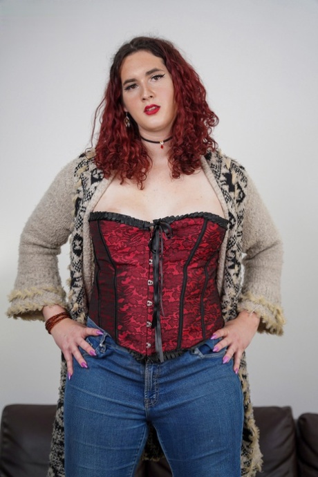 Kurvig rödhårig shemale Lily Fox tar av sig sina jeans och visar sina stora bröst