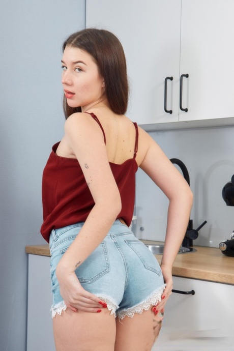 Europeiska tonåringen Jolie Butt exponerar sin söta röv och leker med sin fitta i köket