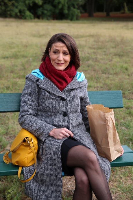 Francuska mama Anya pokazuje nogi w pończochach, jedząc kanapkę na zewnątrz
