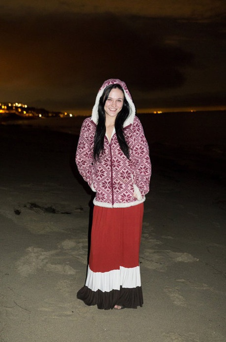 Schattig meisje Logan Drae toont haar flexibiliteit terwijl ze naakt op het strand ligt