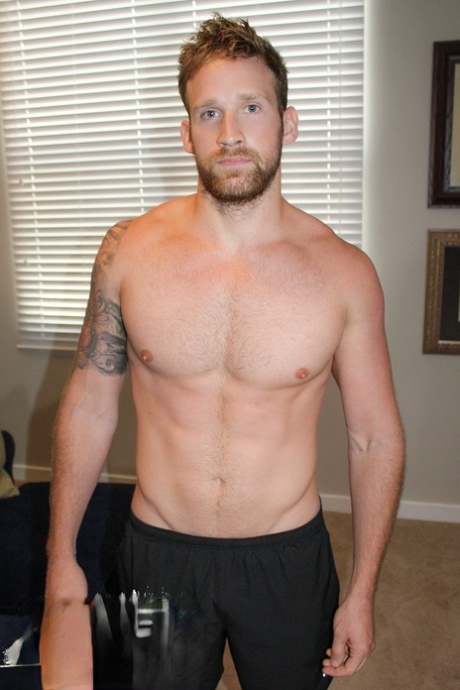 Le bodybuilder gay Logan Carter se déshabille sur son lit et exhibe sa bite et ses muscles.