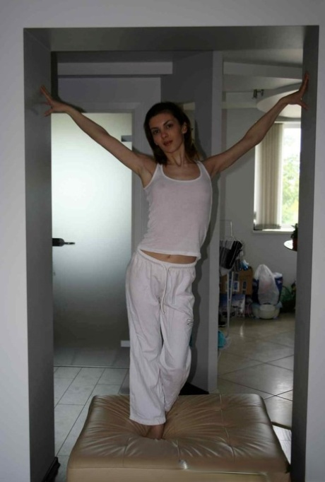 Schlanke Teenagerin zieht ihren Pyjama aus und posiert nackt zu Hause am Morgen