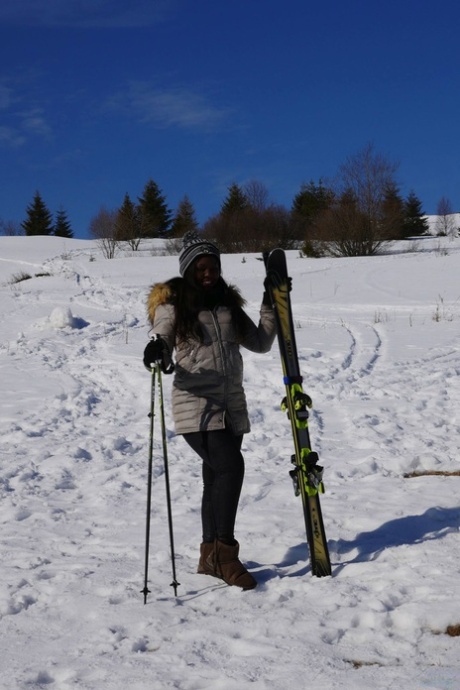 Heißes kenianisches Babe Sunny Star posiert in ihrem Skioutfit im Schnee