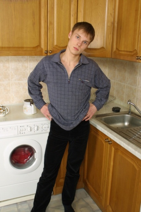 Knappe homo Yury stript in de keuken en masseert zijn ongesneden lul