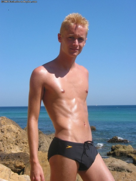 Magere blonde homo Kyle stript zijn Speedos en masturbeert op het strand