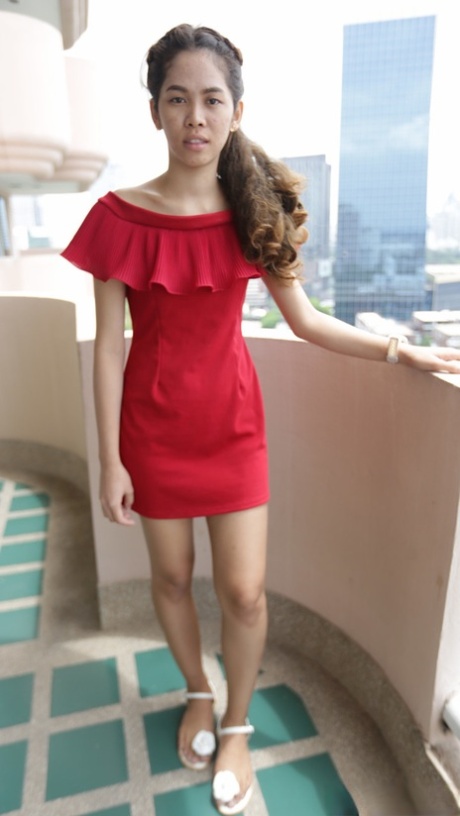 Hermosa chica asiática Mee muestra sus piernas calientes en un vestido rojo corto