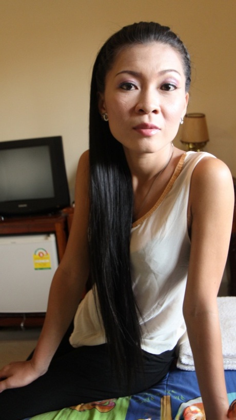 Tynd asiatisk Gi viser sin behårede fisse frem, mens hun klæder sig af til sex