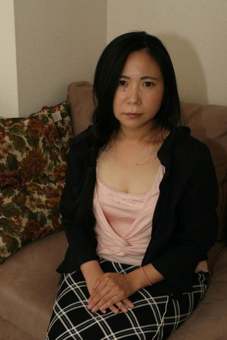 Schattige Japanse oma Yasuko Watanabe stript en masturbeert op de bank