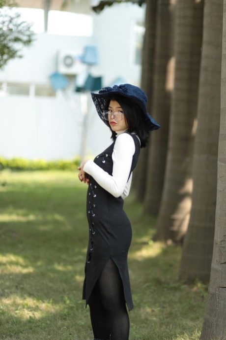 Glamouröses asiatisches Model mit Brille posiert in einem eleganten Outfit in der Öffentlichkeit