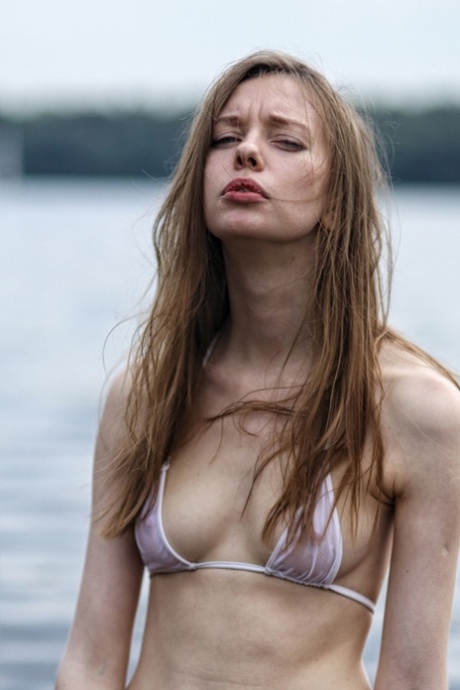 Delgada adolescente morena posando en su pequeño bikini blanco en el agua de mar