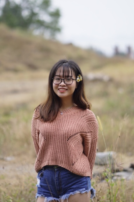 Una splendida ragazza asiatica posa in pantaloncini di jeans e maglione in pubblico