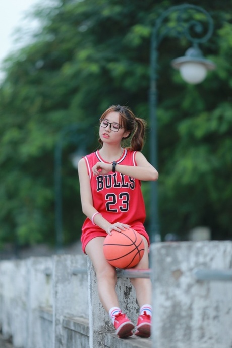 Nerdy asiatisk kvinnelig basketballspiller som poserer i Bulls-trøyen i offentligheten