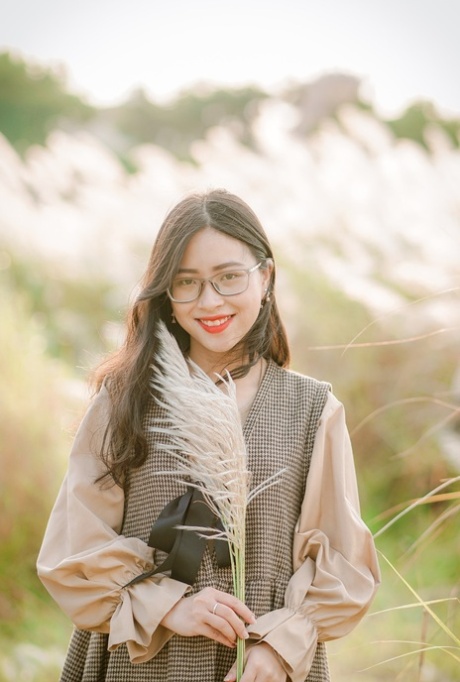 Hübsches asiatisches Mädchen mit Brille posiert in ihrem herrlichen Outfit in der Natur