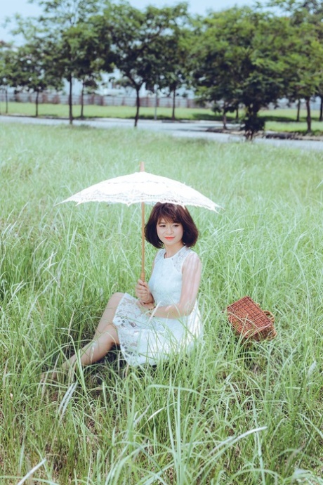 Lindas modelos asiáticas a posar com os seus vestidos brancos no prado