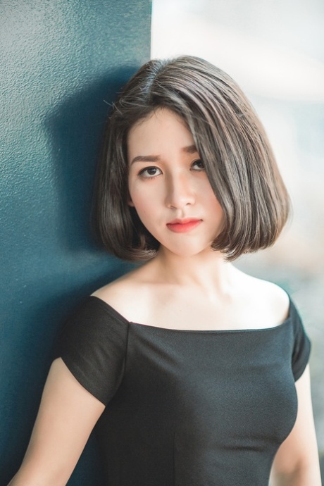 Miúda asiática glamorosa a posar com o seu elegante vestido preto em público