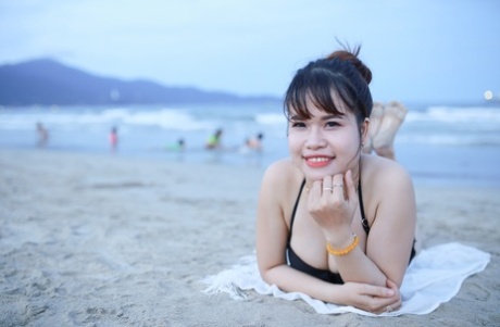 Charming Asian models posing in their black bikinis on the sandy beach