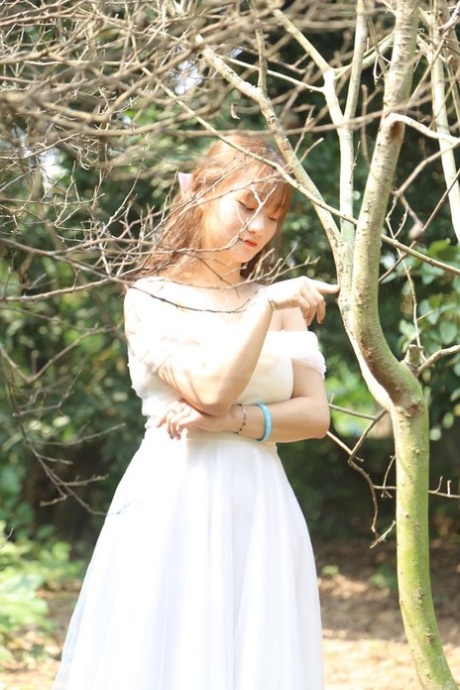 Glamorous Asian girl posing in her elegant white dress outdoors