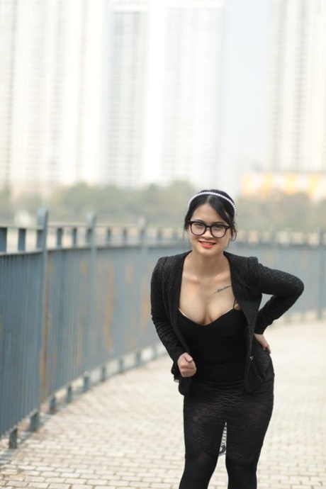 Curvaceous Asian girl with glasses posing in her hot black outfit outdoors