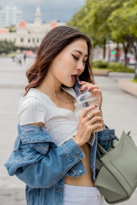 Une fille asiatique à couper le souffle pose en public dans sa tenue sexy et ses talons.