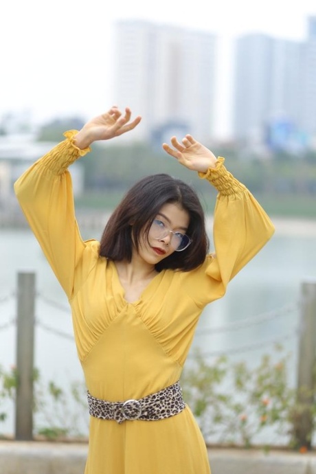 Glamorous Asian girl with eyeglasses Irena poses in her yellow dress in public