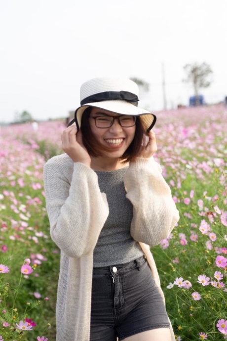 Mooi Aziatisch model met glazen die buiten onder prachtige bloemen stellen