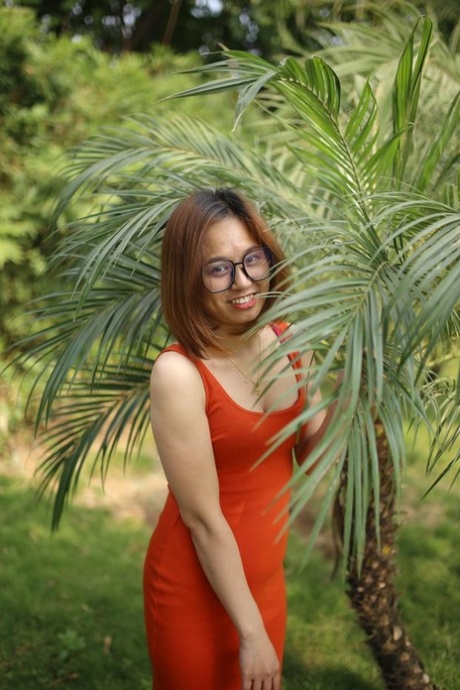 Cute Asian girl with glasses posing in her tight red dress outdoors