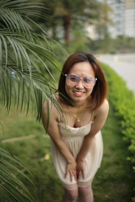 Adorable redheaded babe with glasses posing in her cute dress outdoors