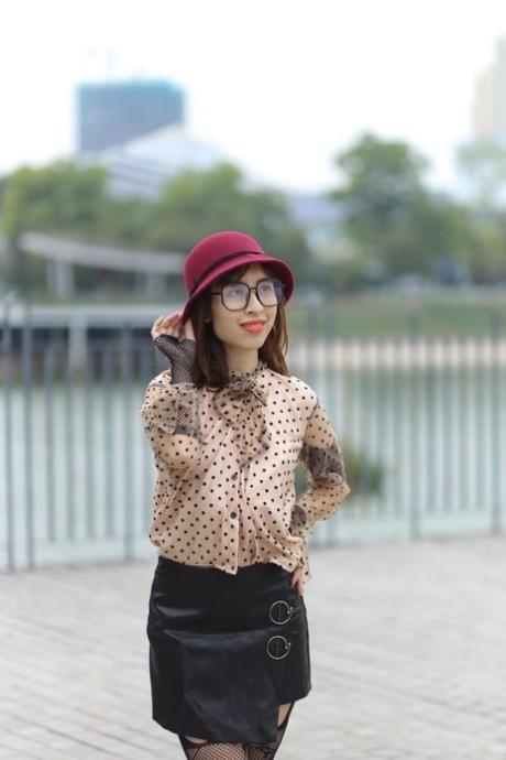 Nerdy Asian model with a hat posing in her cute outfit in public