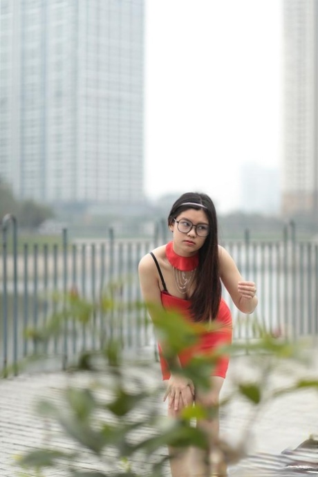 Sweet Asian babe with eyeglasses Natali posing in her red summer dress outside