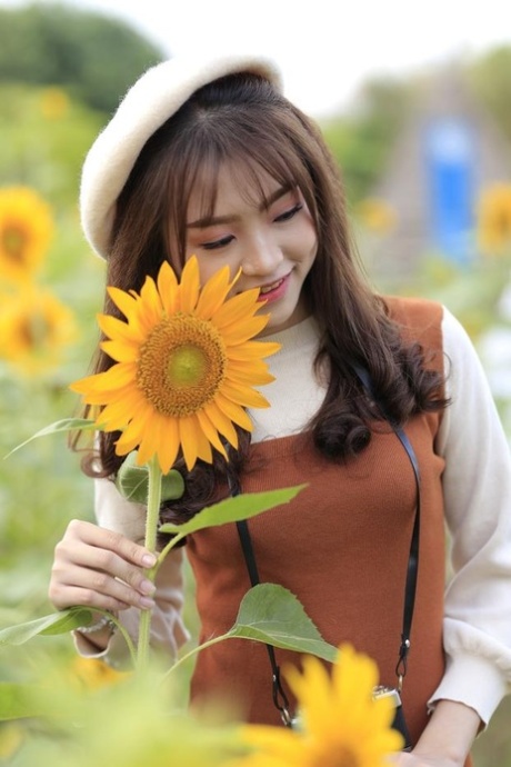 Adorable Asiatique posant dans sa jolie tenue dans le champ de tournesol